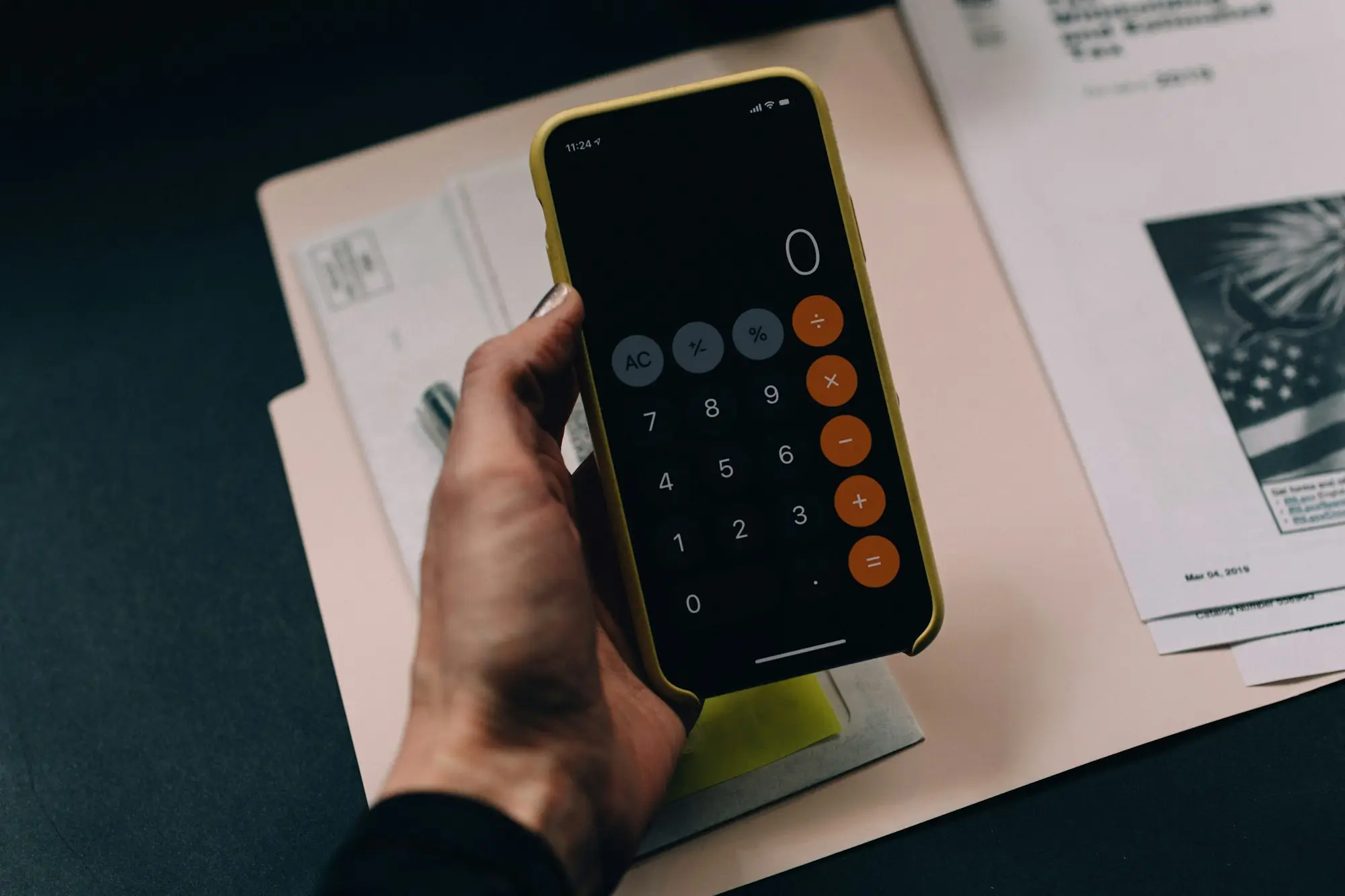 Calculator app on a phone over tax paperwork on a desk