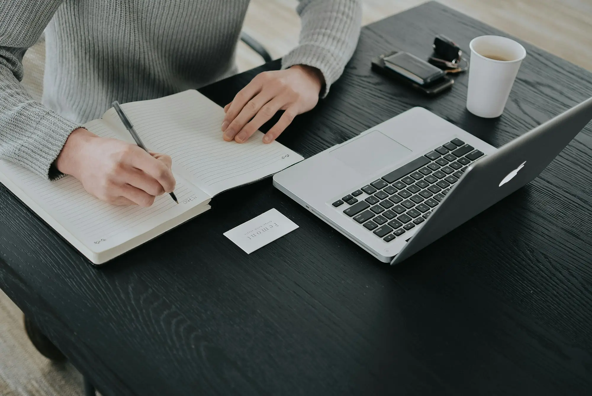 Sole trader working through paperwork beside a laptop in a home office