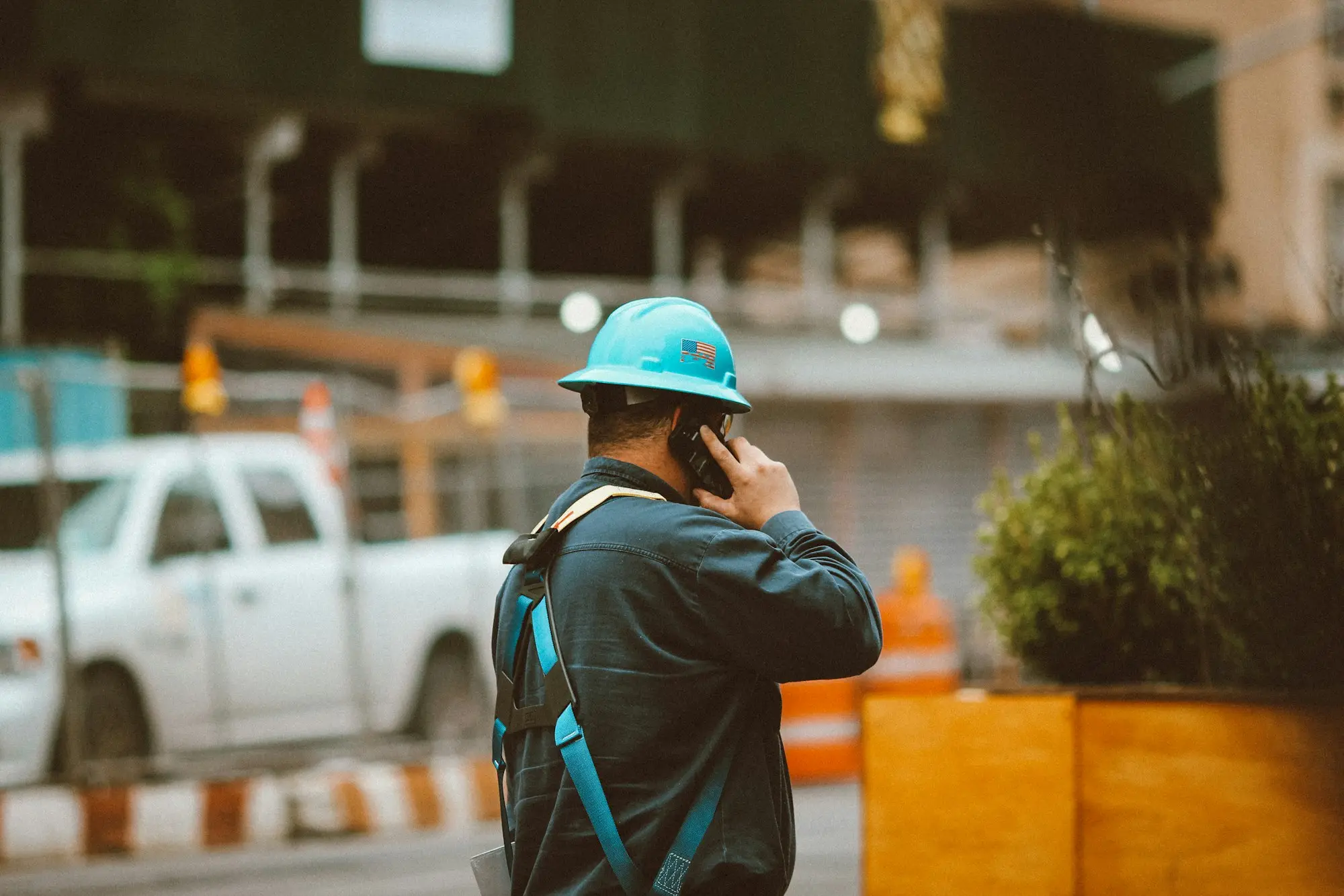Tradie in a hard hat on the phone beside a white ute